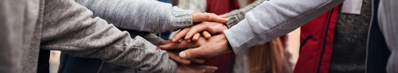 Several people placing their hands on top of each others'.