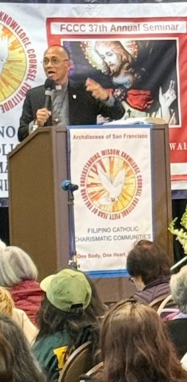 About 1 A photo of a priest speaking on stage