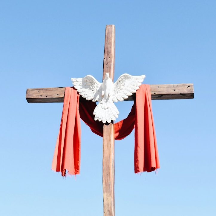 Cross A wooden cross with a red shawl and a small statue of the Holy Spirit in the center
