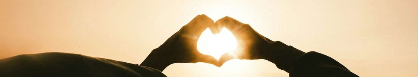 Support Banner 2 Hands shaped into a heart over sunlight.